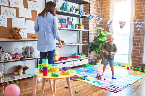 Young caucasian child playing at playschool with teacher Tableau sur Toile
