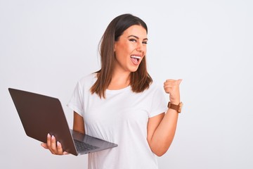 Poster - Beautiful young woman working using computer laptop over white background Pointing to the back behind with hand and thumbs up, smiling confident