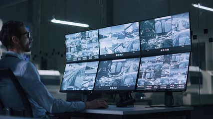 Poster - Industry 4.0 Modern Factory: Security Operator Controls Proper Functioning of Workshop Production Line, Uses Computer with Screens Showing Surveillance Camera Footage Feed. High-Tech Security