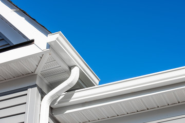 Colonial white gutter guard system,  soffit providing ventilation to the attic, with gray vinyl horizontal siding at a luxury American single family home neighborhood USA