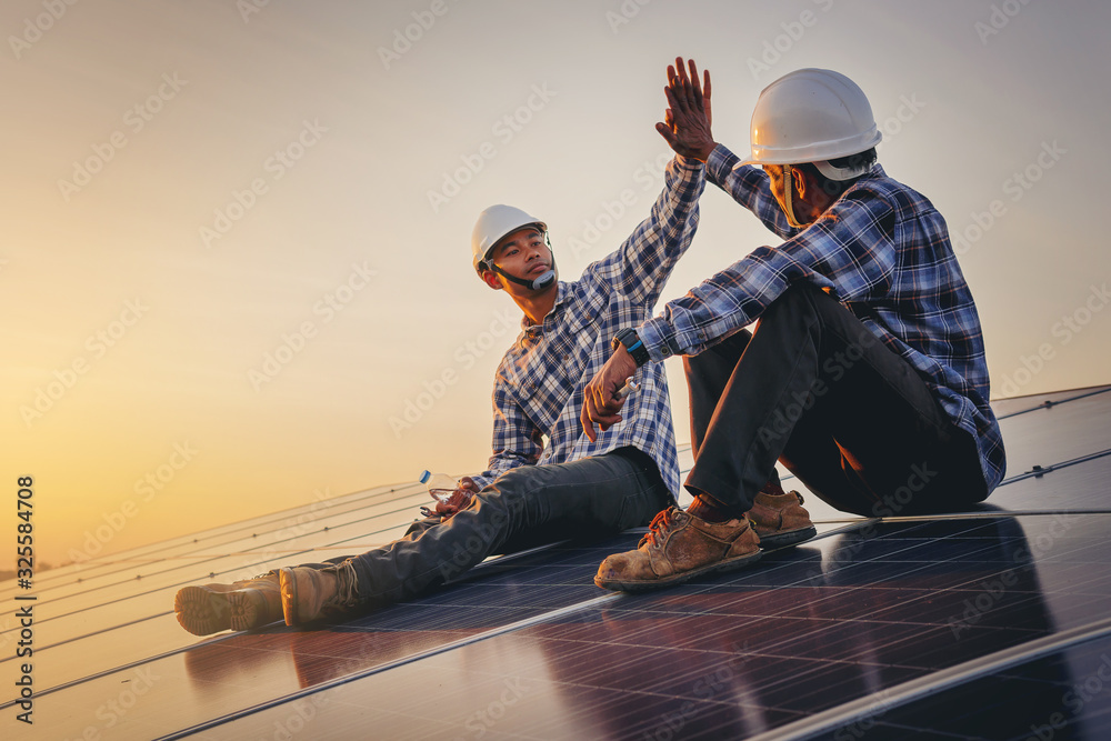 Electrical, instrument technician celebrate their work day done, maintenance electric system by shake hands at solar panel field  - obrazy, fototapety, plakaty 
