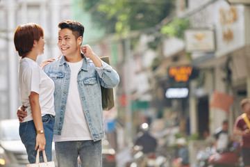 Sticker - Beautiful happy young Vietnamese couple hugging in the street after shopping together