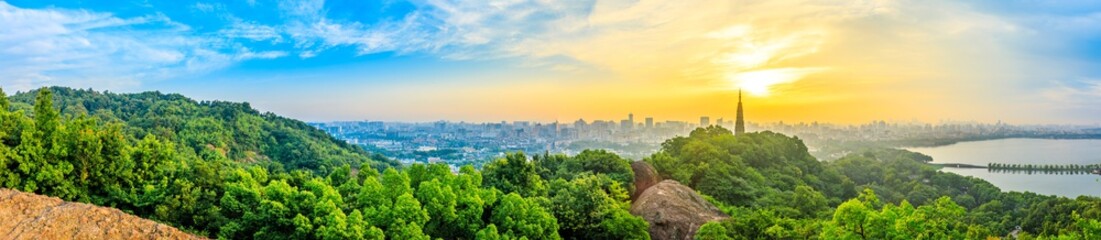 Panoramic city skyline and green mountains at sunrise in Hangzhou,China.