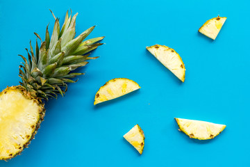 Pineapple - half of fruit and slices - on blue background top-down