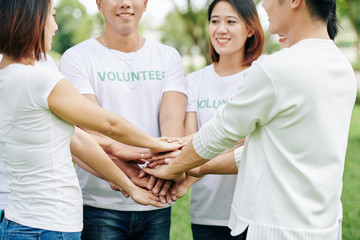 Sticker - Group of volunteers stacking hands before enthusiastically engage in cleaning activity in local park