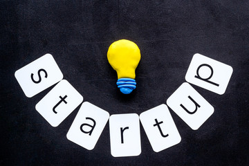 Startup concept with bulb icon on black background top-down