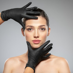  Doctor checks a skin before plastic surgery.  Face skin check before plastic surgery. Beautician touching woman face.Beauty treatments. Plastic surgery doctor is touching face of a patient by hands