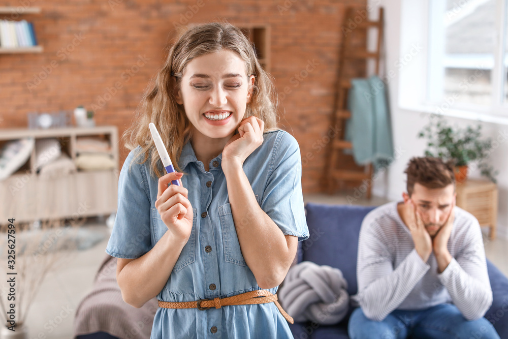 Happy young woman with pregnancy test at home