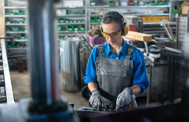 Wall Mural - Woman worker operating a machine tool in metal workshop or factory