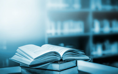Poster - Stack of books in the library and blur bookshelf background