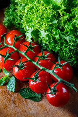 Ripe red fresh tomatoes on the vine. Lettuce and mint leaves.