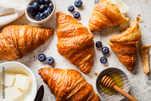 Fotomural Fresh croissants with blueberries, butter and honey, gray background, top view