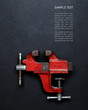 Metalwork tool - red vintage mechanical hand vise clamp on grey background with copy space and Sample text, top view