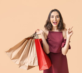 Beautiful young woman with shopping bags on color background