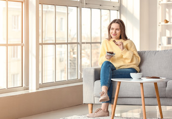 Beautiful young woman eating chocolate at home