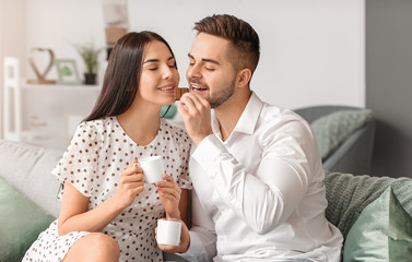 Wall Mural - Beautiful young couple eating chocolate at home