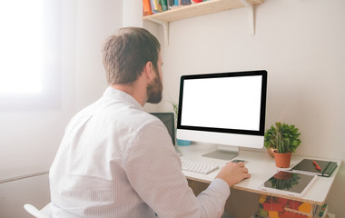 Young man looking at computer monitor during working day in home office