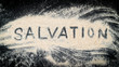 Flat lay of SALVATION word written on white sand