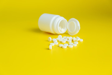 White pills and white bottle on a bright yellow background, healthy and medicine concept. Minimalism. Copy space