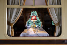  Interior View From A Railway Platform Of A First Class Dining Area Located On A Famous Railway. The Lit Table Lamp And Silver Service Can Be Seen.