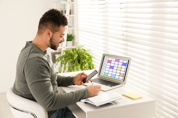 Wall Mural - Young man planning his schedule with calendar app on laptop in office