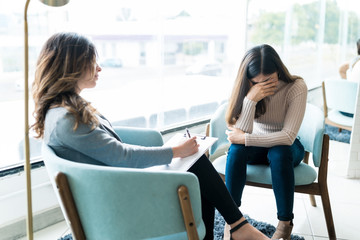 Therapist Making Notes While Sitting With Sad Patient