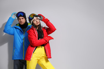 Wall Mural - Couple wearing stylish winter sport clothes on light grey background. Space for text