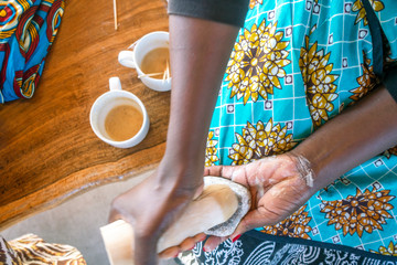 Crushing root on the stone to use that pulp to do traditional African facial make up