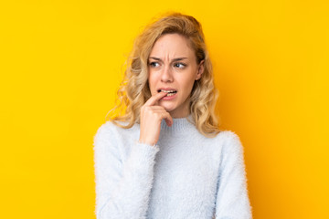 Wall Mural - Young blonde woman isolated on yellow background nervous and scared