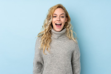 Canvas Print - Young blonde woman wearing a sweater isolated on blue background with surprise facial expression