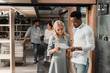© LIGHTFIELD STUDIOS - handsome african american businessman looking at document with pretty colleague while multicultural friends standing on background