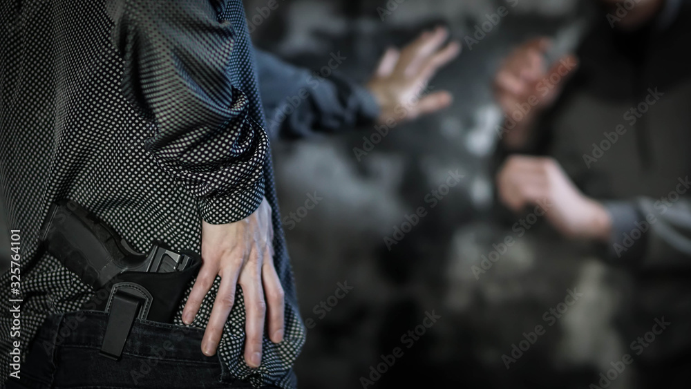 Woman reaching for handgun to defend against attacker. Women's personal defense and concealed carry concept - obrazy, fototapety, plakaty 