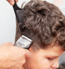 Wall Mural - The hairdresser cuts the hair of a boy with a machine