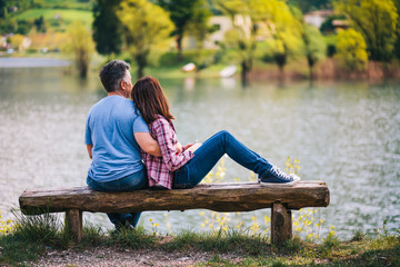 Young couple sitting on bench under a tree at lake in Italy.