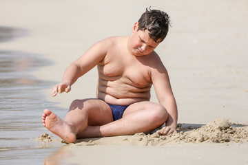 Wall Mural - A boy plays in the sand on the seashore