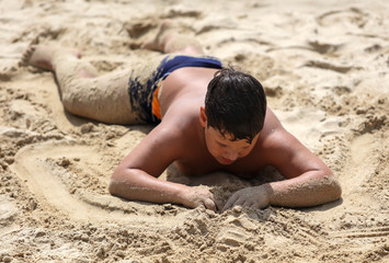 Wall Mural - A boy plays in the sand on the seashore