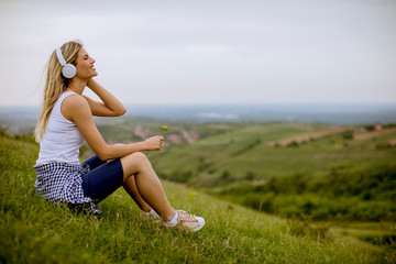 Wall Mural - Young woman in nature listening to music on headphones