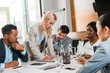 © LIGHTFIELD STUDIOS - selective focus of attractive businesswoman writing in notebook near multicultural colleagues sitting at desk in conference hall