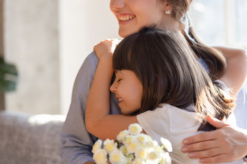 Wall Mural - Loving little daughter hug mommy greeting presenting flowers