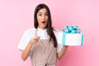 © luismolinero - Young woman with a big cake over isolated background surprised and pointing front