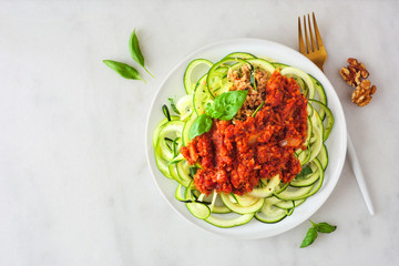 Wall Mural - Zucchini pasta topped with meatless walnut cauliflower bolognese. Top view on a white marble background. Healthy eating, plant-based meat substitute concept.