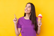 Young brunette woman with a cornet ice cream over isolated yellow background intending to realizes the solution while lifting a finger up