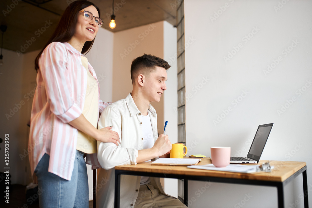 attractive beautiful girl in eyeglasses standing next to her sitting boyfriend dreaming about luxury life. close up side view photo, future plans