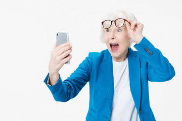 Senior woman very happy and excited using smartphone over isolated background