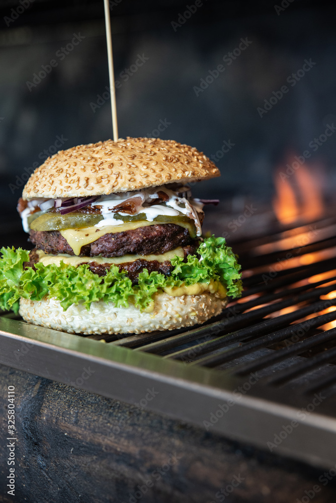 Obraz na płótnie Duży burger ze świeżymi warzywami i serem owinięty w papier ekologiczny. Grillowana kanapka meksykańska na drewnianym stole w stylu industrialnym. Hamburger na wynos z widokiem na ogród. w salonie