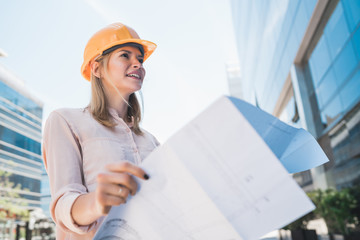 Professional architect holding blueprints outdoors.