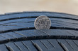 Closeup of checking tire tread wear depth of old tire using a quarter coin. Concept of automobile safety, maintenance, and repair