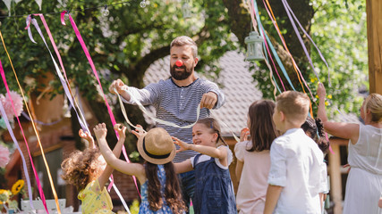 Wall Mural - Man with kids on birthday party playing outdoors in garden in summer.