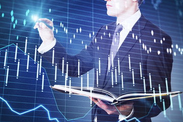 Wall Mural - Businessman holding book and drawing business chart hologram.