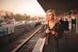 © Cavan Images - Young thoughtful woman using smart phone while waiting for train